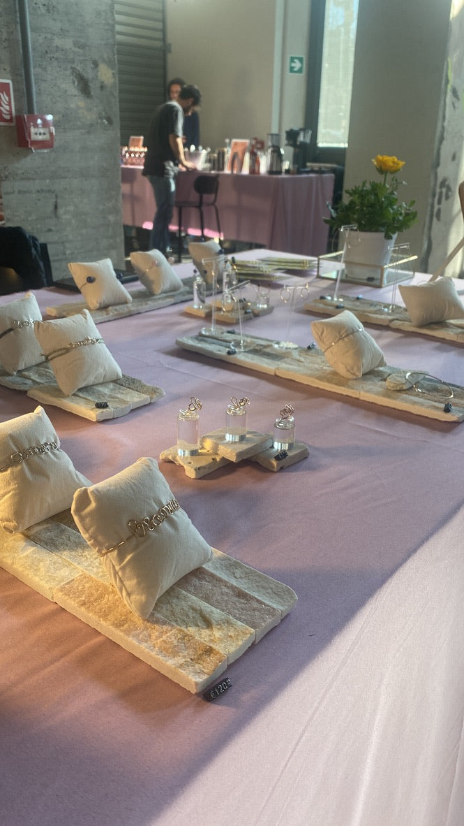 Il banco allestito per un pop-up: gioielli su cuscini e vassoi di legno.